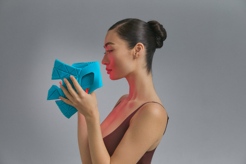 Modella di profilo che tiene la Blue Green Mask Lift color verde acqua, luce rossa accesa