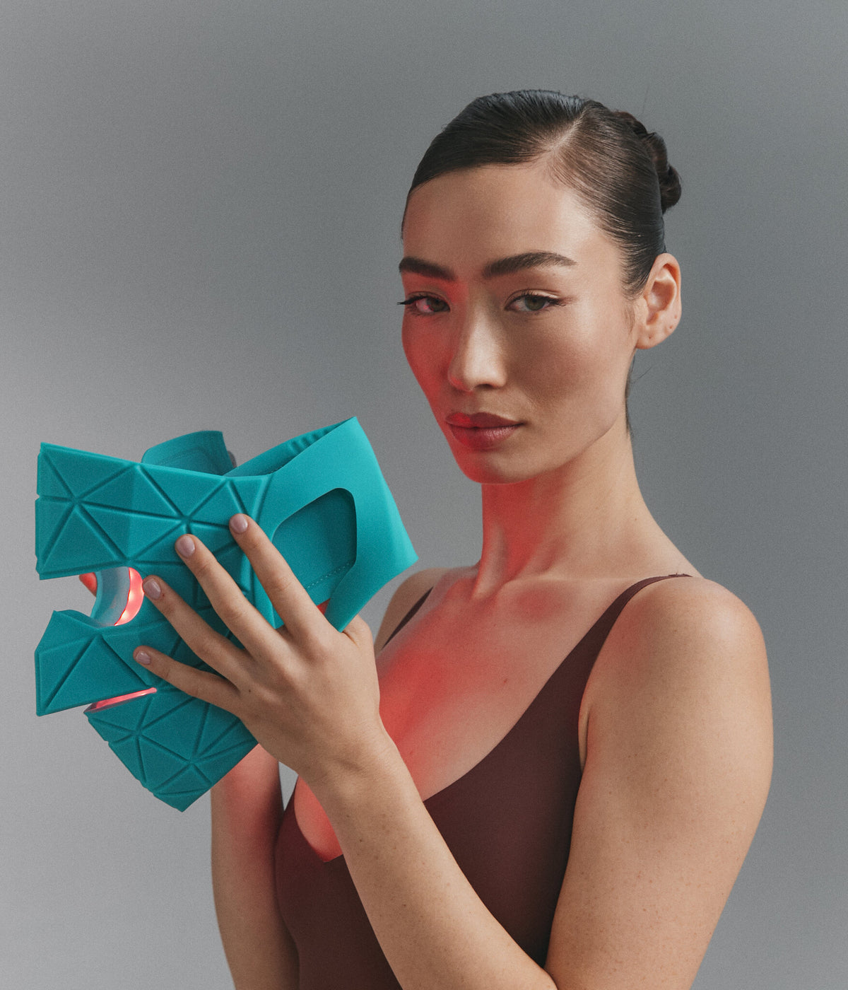 Modella che tiene la Blue Green Mask Lift, luce rossa accesa