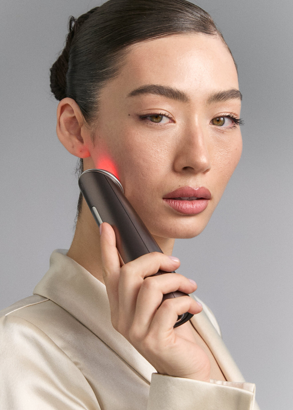 Model holding Photo Plus Deep Lift to her cheek, portrait view